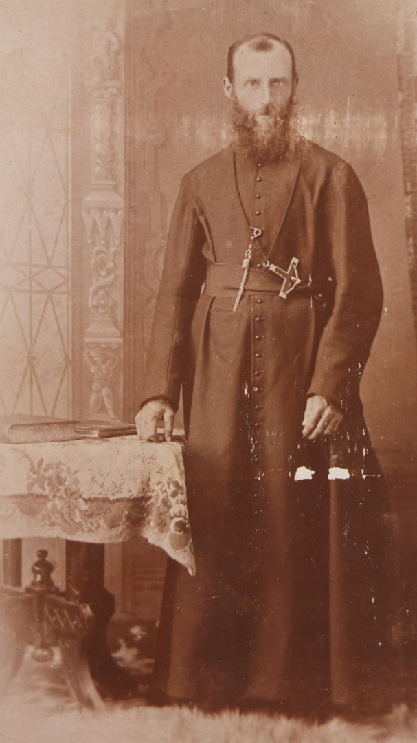 Lot 019 - Antique Cabinet Card Photograph Of A Bearded Priest In Black Robe With Large Pectoral Crucifix Tucked In Belt, Frank Lariviere, Photographer, Central Falls & Pawtucket, Rhode Island