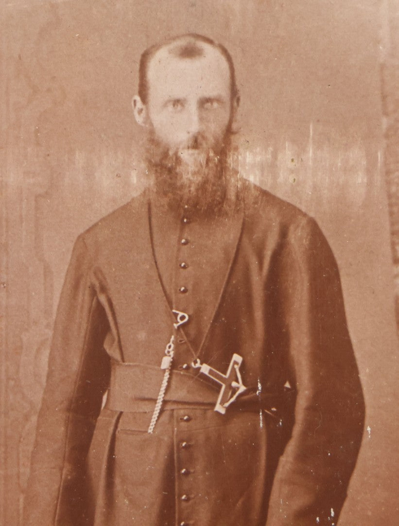 Lot 019 - Antique Cabinet Card Photograph Of A Bearded Priest In Black Robe With Large Pectoral Crucifix Tucked In Belt, Frank Lariviere, Photographer, Central Falls & Pawtucket, Rhode Island