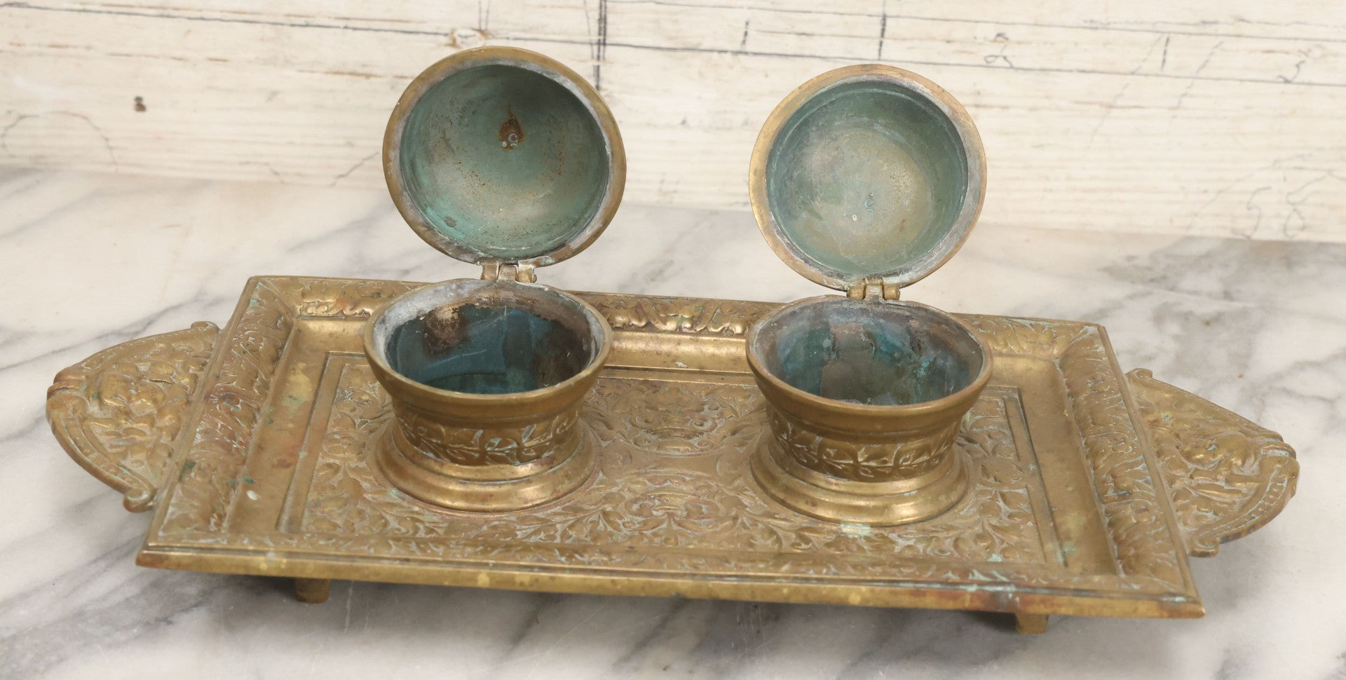 Lot 027 - Antique Cast Brass Double Inkwell And Desk Tray With Cherub And Green Man Motifs, Hinged Lids, Underside Marked 3143, No Inserts