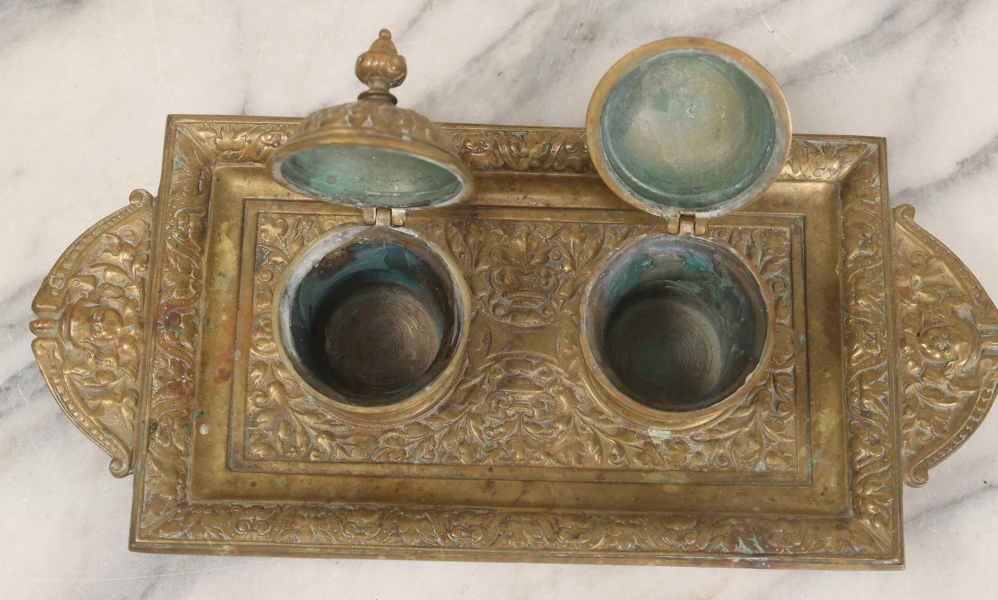 Lot 027 - Antique Cast Brass Double Inkwell And Desk Tray With Cherub And Green Man Motifs, Hinged Lids, Underside Marked 3143, No Inserts