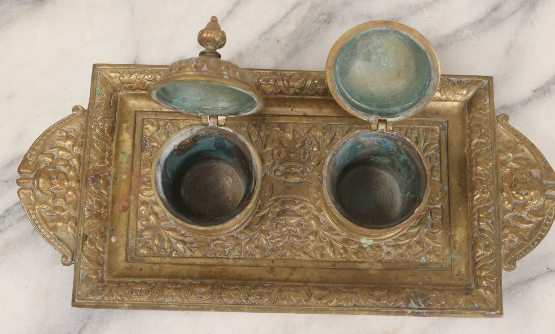 Lot 027 - Antique Cast Brass Double Inkwell And Desk Tray With Cherub And Green Man Motifs, Hinged Lids, Underside Marked 3143, No Inserts