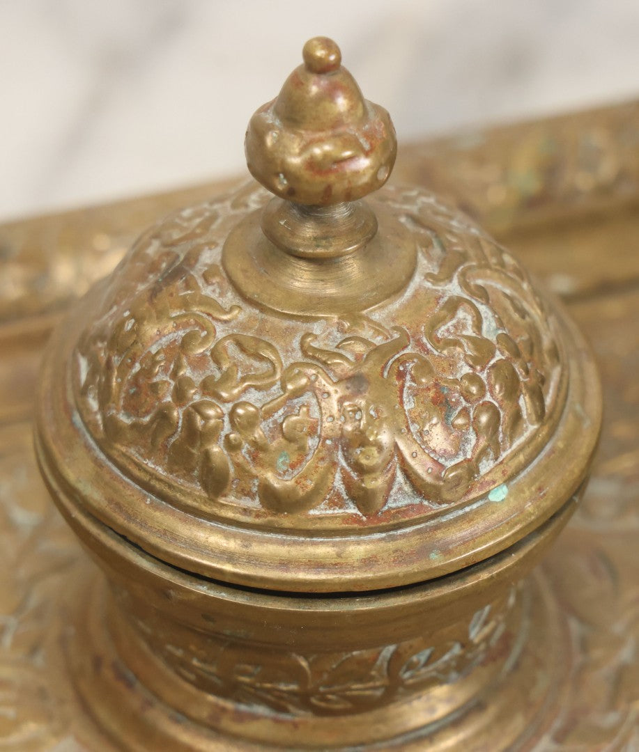 Lot 027 - Antique Cast Brass Double Inkwell And Desk Tray With Cherub And Green Man Motifs, Hinged Lids, Underside Marked 3143, No Inserts