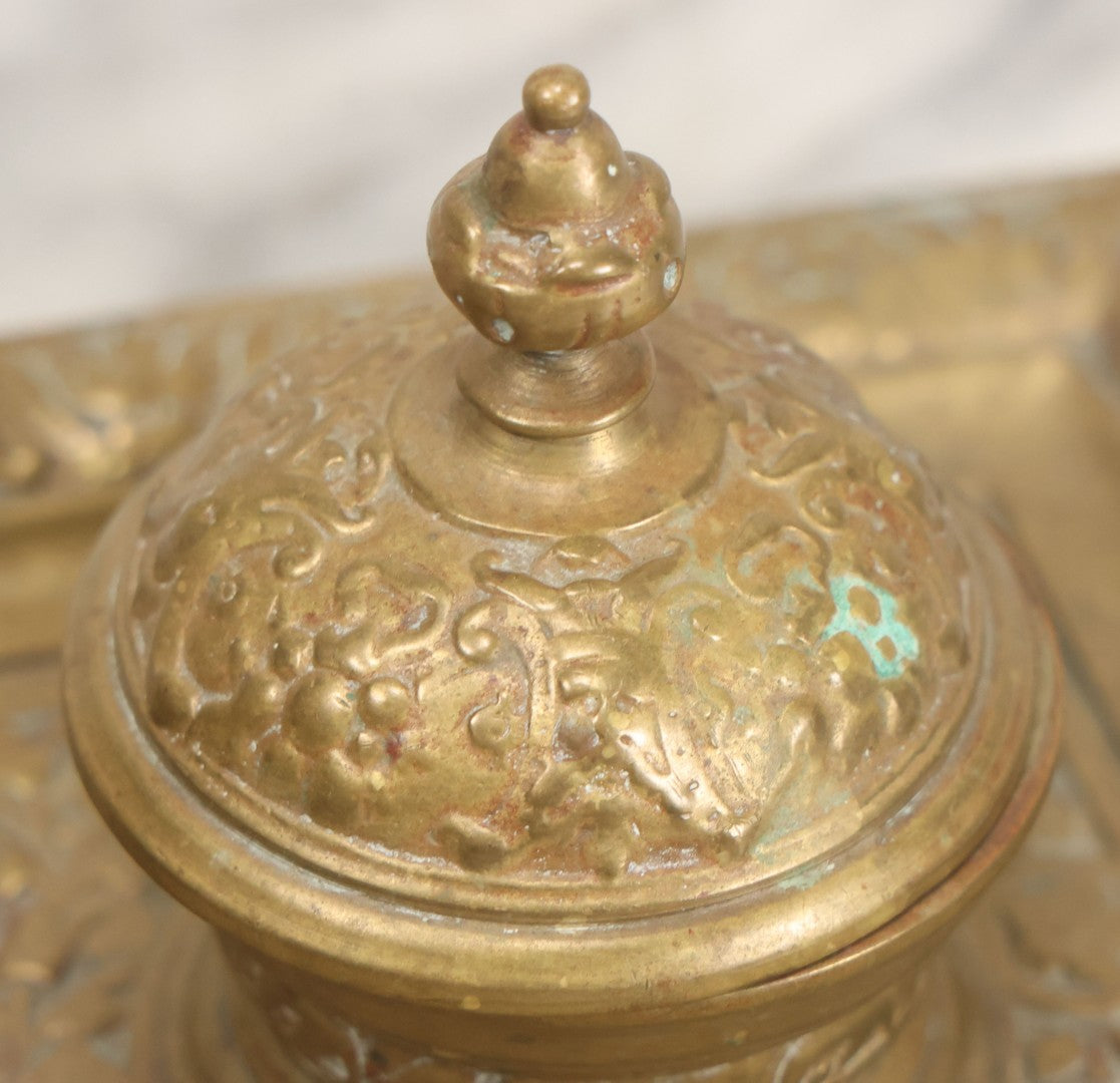 Lot 027 - Antique Cast Brass Double Inkwell And Desk Tray With Cherub And Green Man Motifs, Hinged Lids, Underside Marked 3143, No Inserts