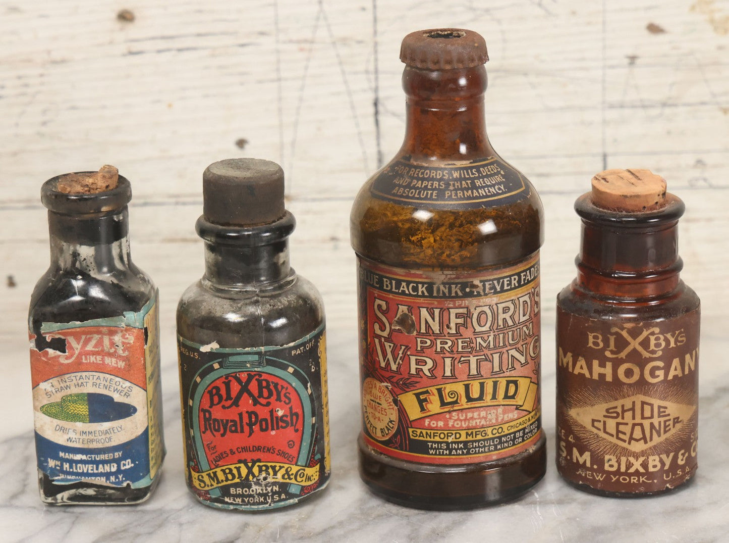 Lot 040 - Grouping Of Four Vintage Ink And Polish Glass Bottles With Paper Labels Including Dyzit Straw Hat Renewer, Sanford's Premium Writing Fluid, Bixby Mahogany Shoe Cleaner, And Bixby Royal Shoe Polish