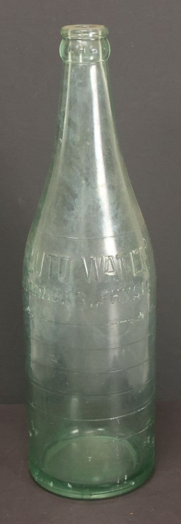 Lot 048 - Antique Pluto Water Green Tinted Clear Glass Bottle With Underside Embossed Devil Motif Logo, "America's Physic", 11" Height
