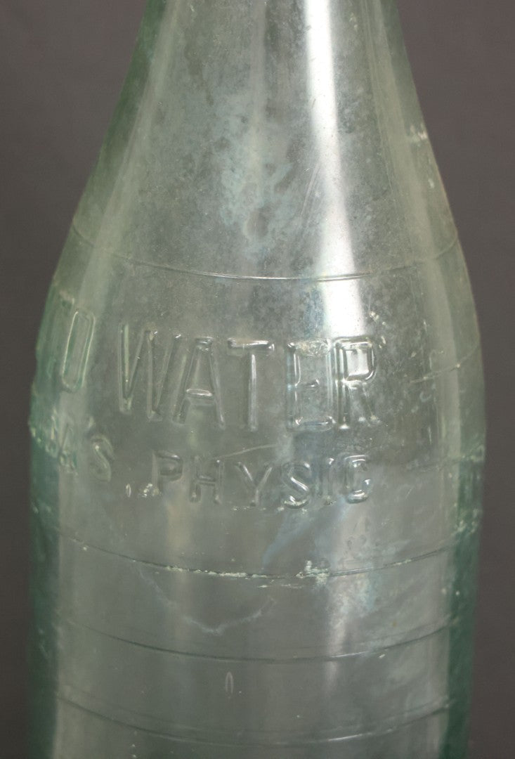 Lot 048 - Antique Pluto Water Green Tinted Clear Glass Bottle With Underside Embossed Devil Motif Logo, "America's Physic", 11" Height