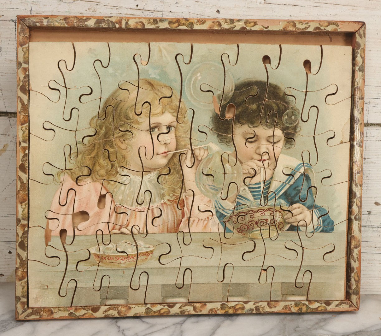 Lot 062 - Antique Double Sided Victorian Lithographed Wood Cut Jigsaw Puzzle With Scene Of Children In Costume With Clown And Children Blowing Bubbles, With Original Box And Partial Lithographed Lid