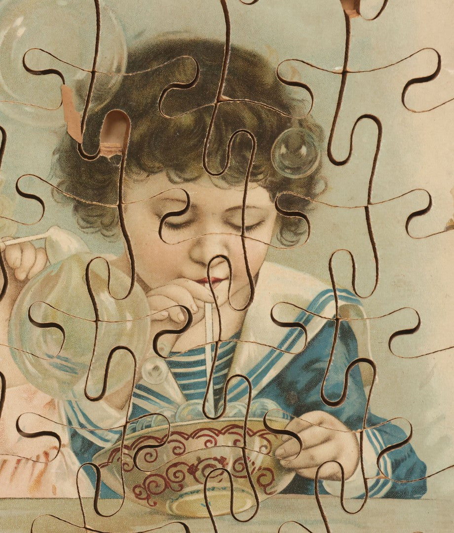 Lot 062 - Antique Double Sided Victorian Lithographed Wood Cut Jigsaw Puzzle With Scene Of Children In Costume With Clown And Children Blowing Bubbles, With Original Box And Partial Lithographed Lid