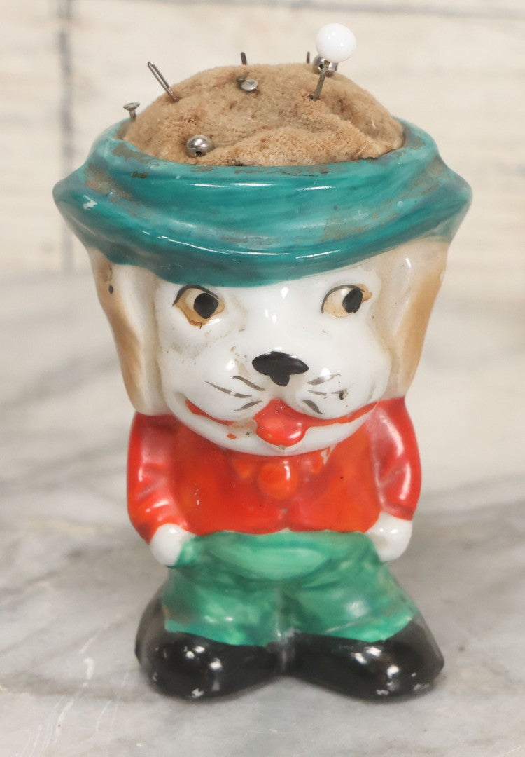Lot 077 - Vintage Novelty Painted Porcelain Anthropomorphic Dog Caricature Pin Cushion, Made In Japan, With Several Ball Head Sewing Pins, 3-1/4" Height