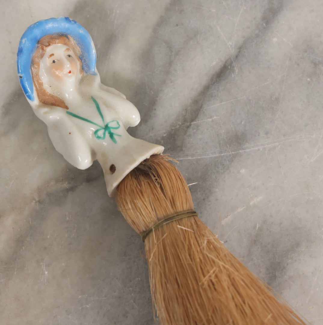 Lot 078 - Vintage Porcelain Lady With Blue Hat, Green Bow, Straw Dresser Brush, Made In Japan, Note Crack, Repair, 5-1/2" Length