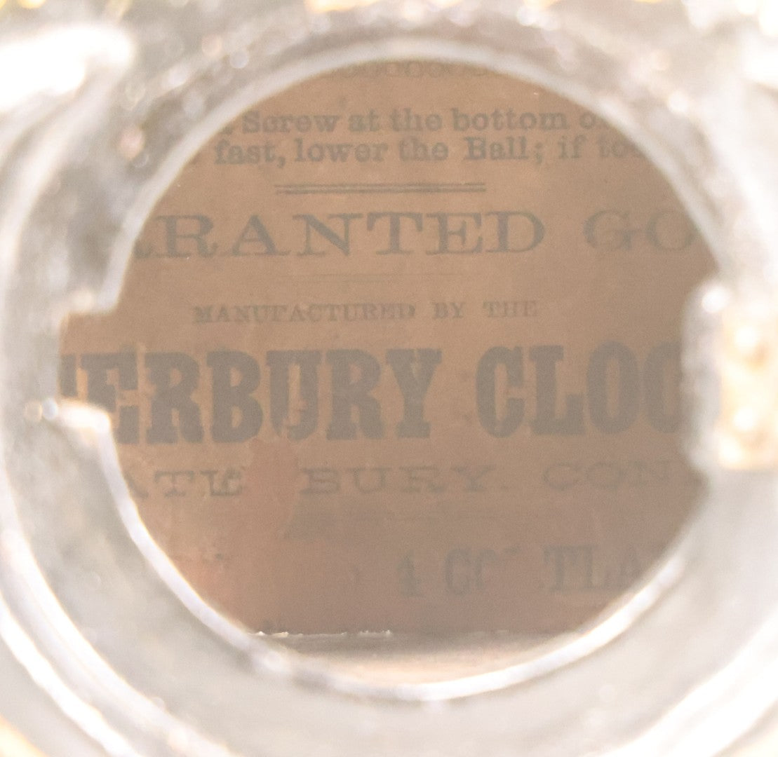 Lot 006 - Antique Metal And Wood Mantel Clock With Hand Painted Details, Paper Clock Face, And Domed Pendulum Window, With Paper Label Inside, Manufactured By The Waterbury Clock Co., Waterbury, Connecticut, Untested, No Pendulum, 13-1/8" H