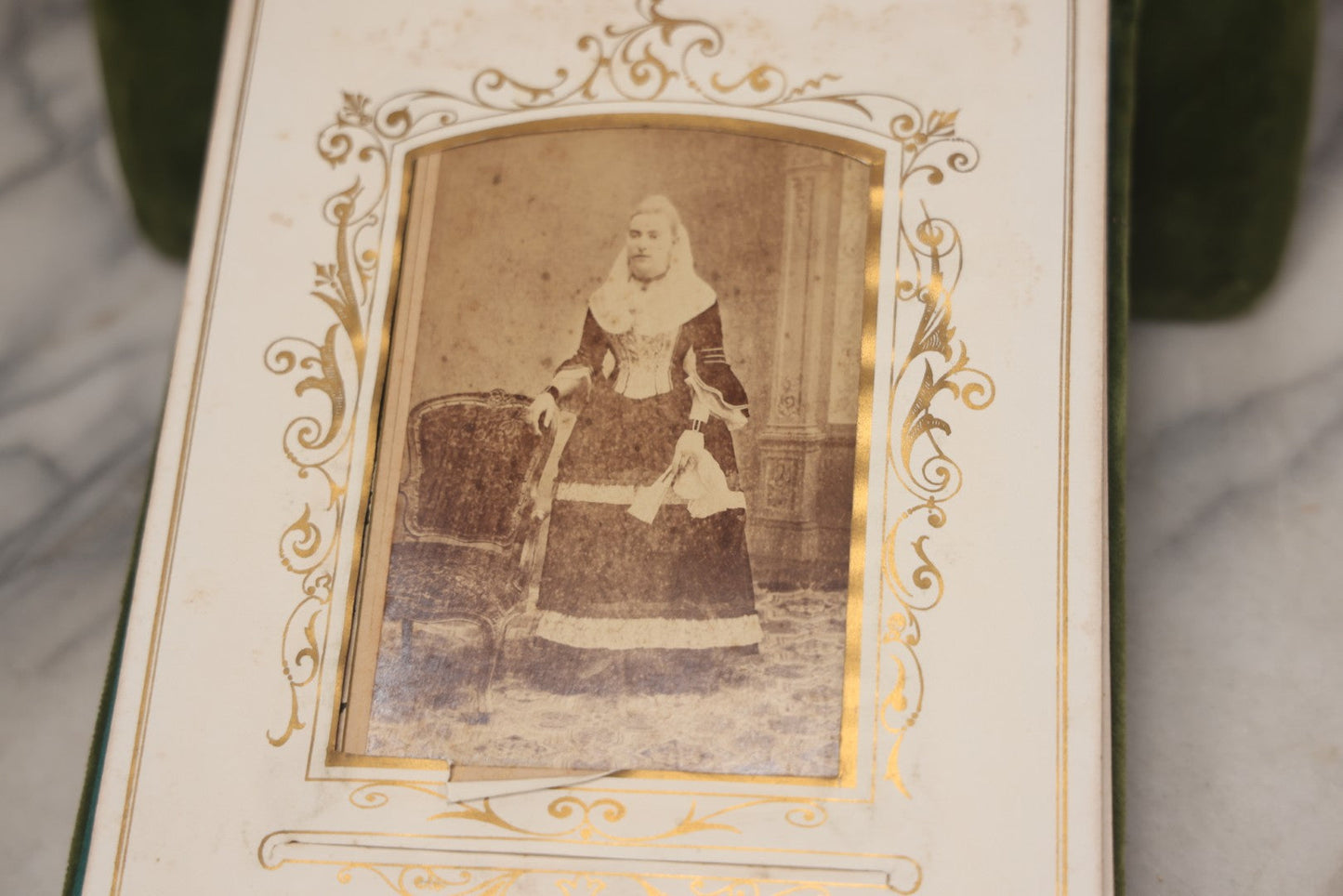 Lot 010 - Antique Victorian Green Velvet Display Photo Album With Stand And Tilt Down Cover, Brass Adornments, Containing 12 Cabinet Card And 24 C.D.V. Photographs And Images, Including Man Posing With Rifle, Sailor In Uniform, And Men Smoking