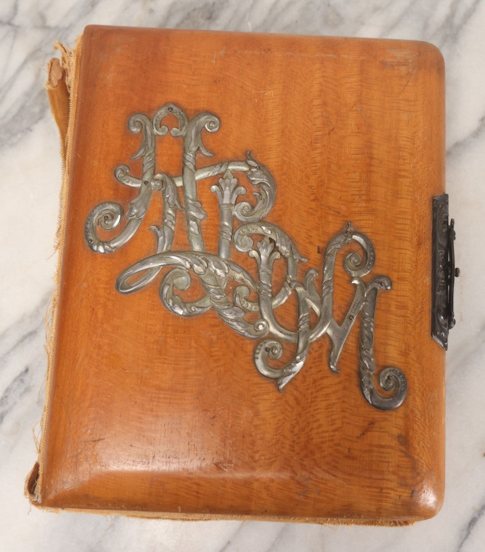 Lot 012 - Antique Victorian Photo Album With Wood Cover And Silverplate Emblem, Containing Twenty Antique Photographs Of Various Types, Including Man In Office, Children With Pram, Man With White Beard, Note Binding Wear Cover Loosening