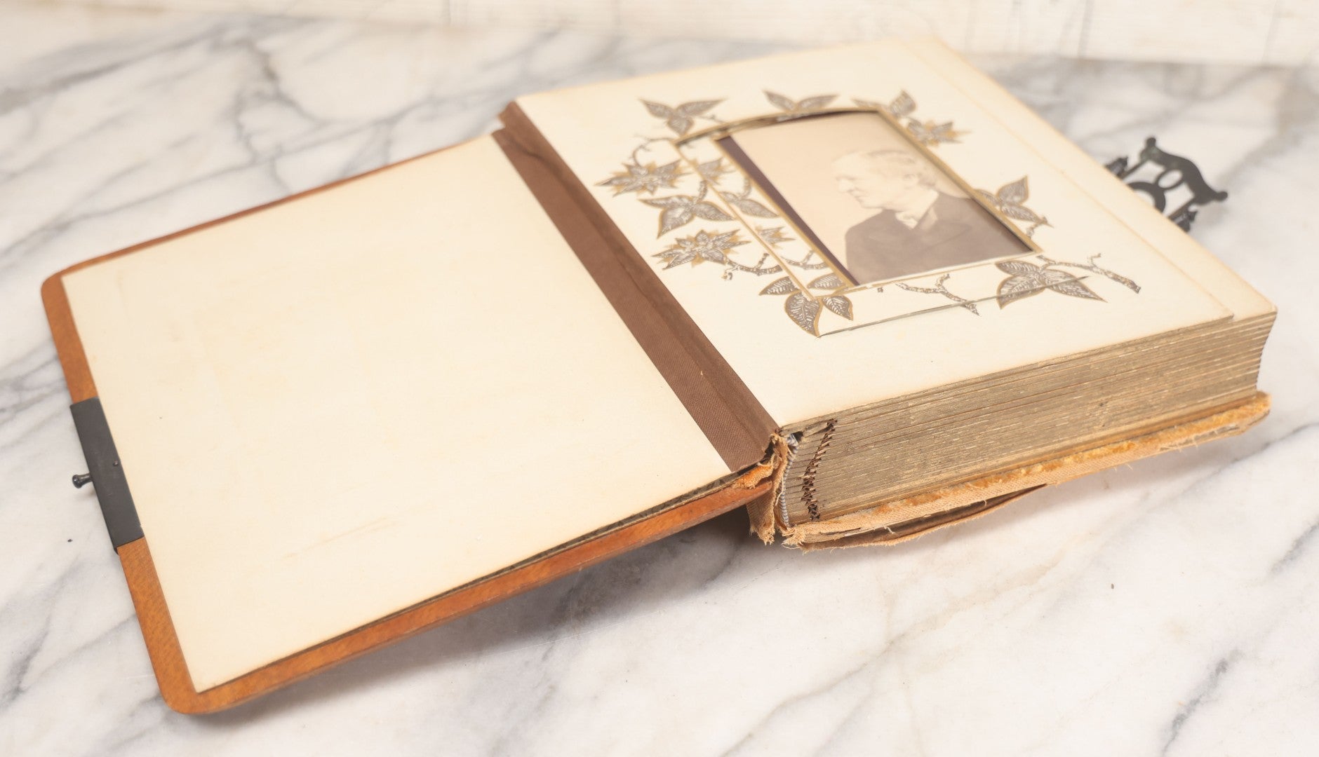 Lot 012 - Antique Victorian Photo Album With Wood Cover And Silverplate Emblem, Containing Twenty Antique Photographs Of Various Types, Including Man In Office, Children With Pram, Man With White Beard, Note Binding Wear Cover Loosening