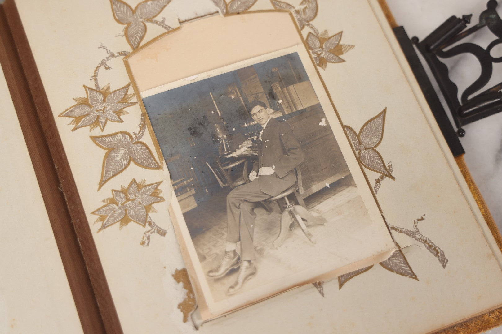 Lot 012 - Antique Victorian Photo Album With Wood Cover And Silverplate Emblem, Containing Twenty Antique Photographs Of Various Types, Including Man In Office, Children With Pram, Man With White Beard, Note Binding Wear Cover Loosening