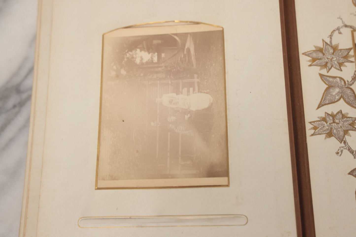 Lot 012 - Antique Victorian Photo Album With Wood Cover And Silverplate Emblem, Containing Twenty Antique Photographs Of Various Types, Including Man In Office, Children With Pram, Man With White Beard, Note Binding Wear Cover Loosening