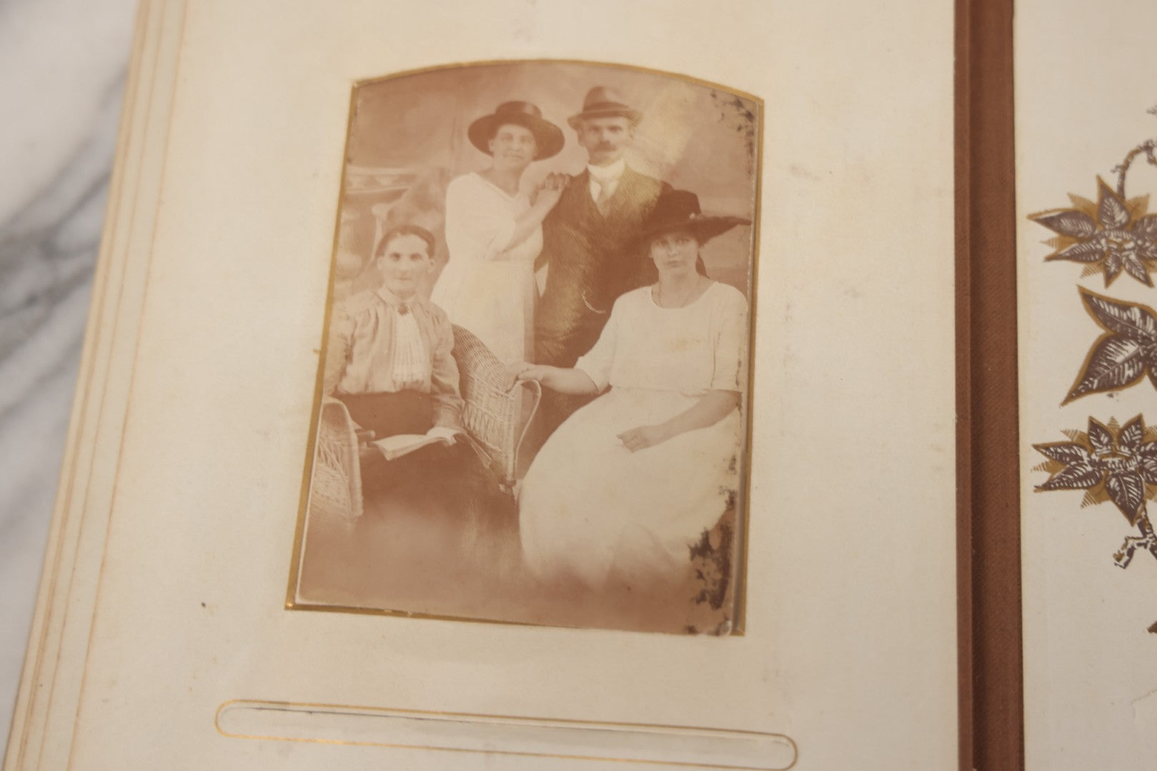 Lot 012 - Antique Victorian Photo Album With Wood Cover And Silverplate Emblem, Containing Twenty Antique Photographs Of Various Types, Including Man In Office, Children With Pram, Man With White Beard, Note Binding Wear Cover Loosening