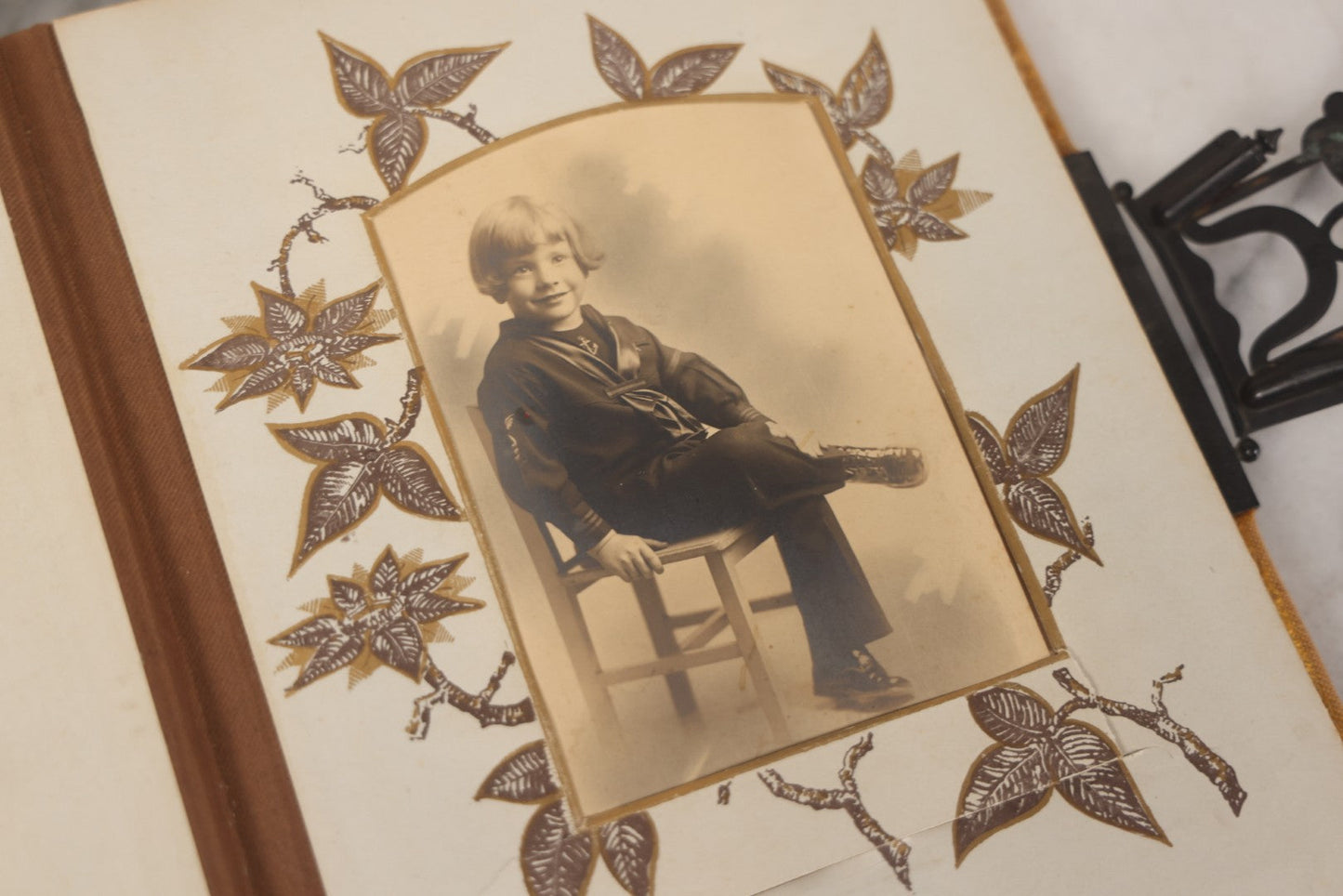 Lot 012 - Antique Victorian Photo Album With Wood Cover And Silverplate Emblem, Containing Twenty Antique Photographs Of Various Types, Including Man In Office, Children With Pram, Man With White Beard, Note Binding Wear Cover Loosening