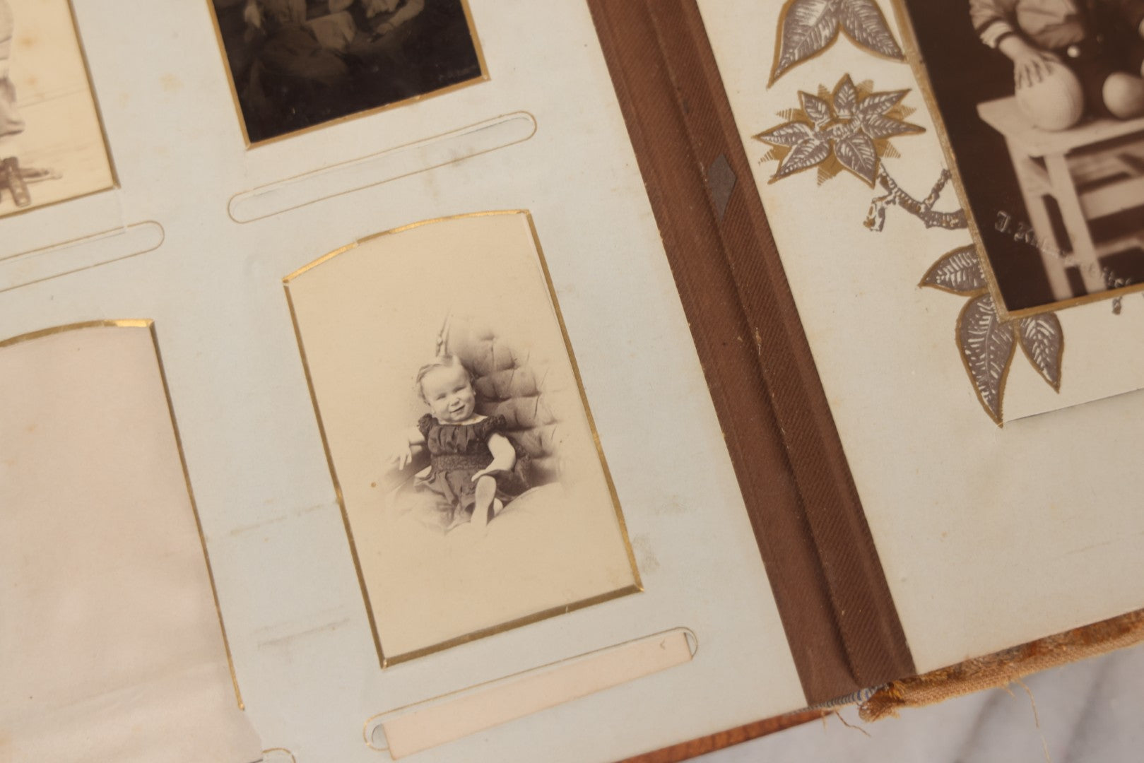 Lot 012 - Antique Victorian Photo Album With Wood Cover And Silverplate Emblem, Containing Twenty Antique Photographs Of Various Types, Including Man In Office, Children With Pram, Man With White Beard, Note Binding Wear Cover Loosening