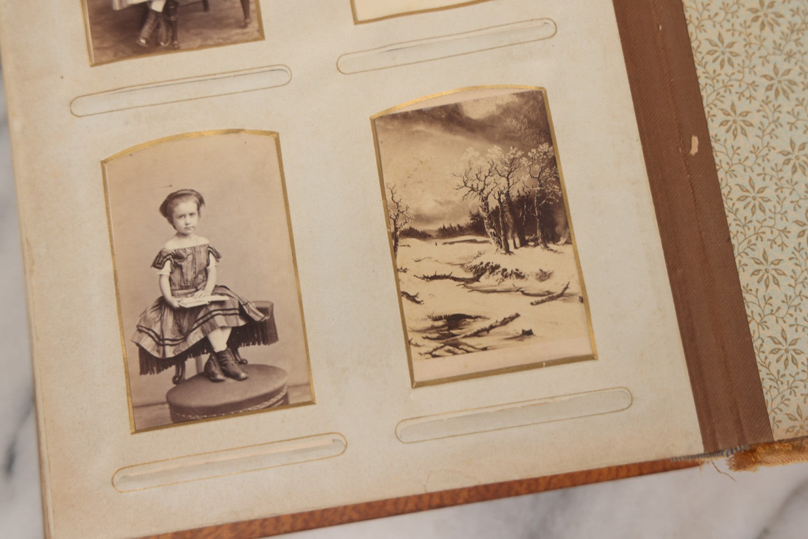 Lot 012 - Antique Victorian Photo Album With Wood Cover And Silverplate Emblem, Containing Twenty Antique Photographs Of Various Types, Including Man In Office, Children With Pram, Man With White Beard, Note Binding Wear Cover Loosening