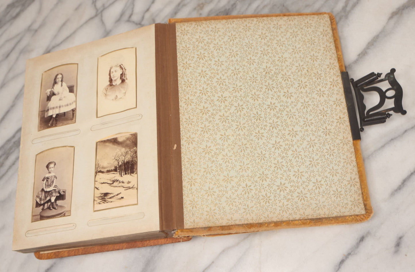 Lot 012 - Antique Victorian Photo Album With Wood Cover And Silverplate Emblem, Containing Twenty Antique Photographs Of Various Types, Including Man In Office, Children With Pram, Man With White Beard, Note Binding Wear Cover Loosening