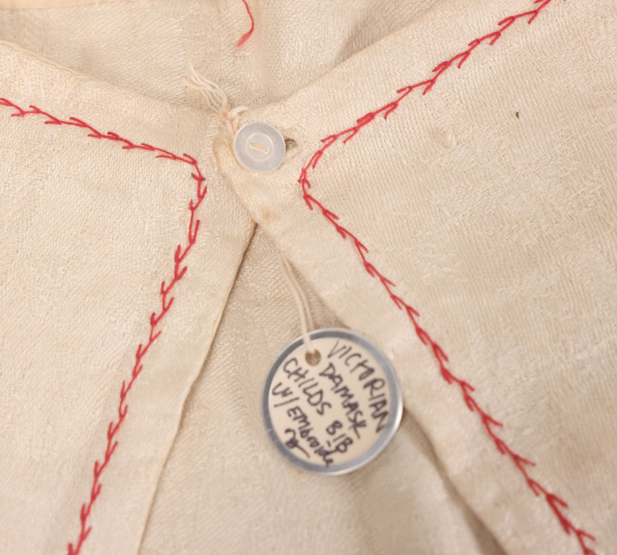 Lot 035 - Antique Damask Textile Fabric Bib With Detailed Red Embroidery Featuring All Seeing Eye, Comb And Brush And Hairpin Motifs