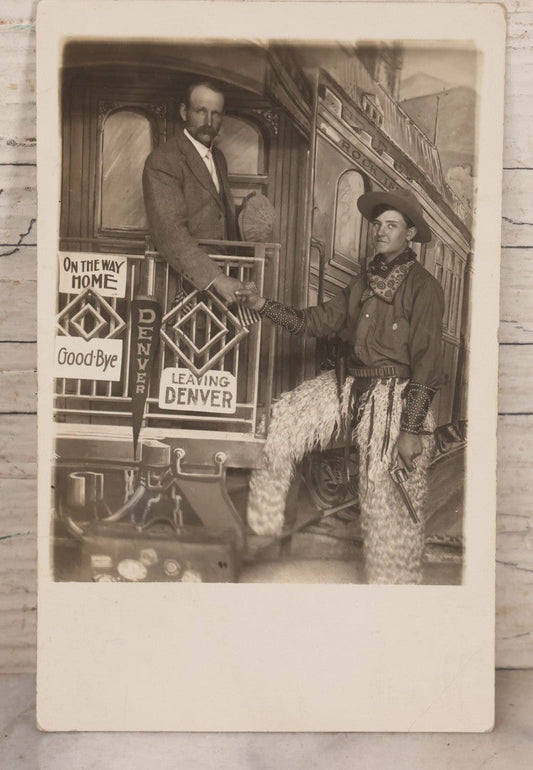 Lot 083 - Antique Real Photo Postcard R.P.P.C. Showing Young Man Dressed As Cowboy Shaking Hands With Older Man On Faux Train Photography Set In Denver, Colorado