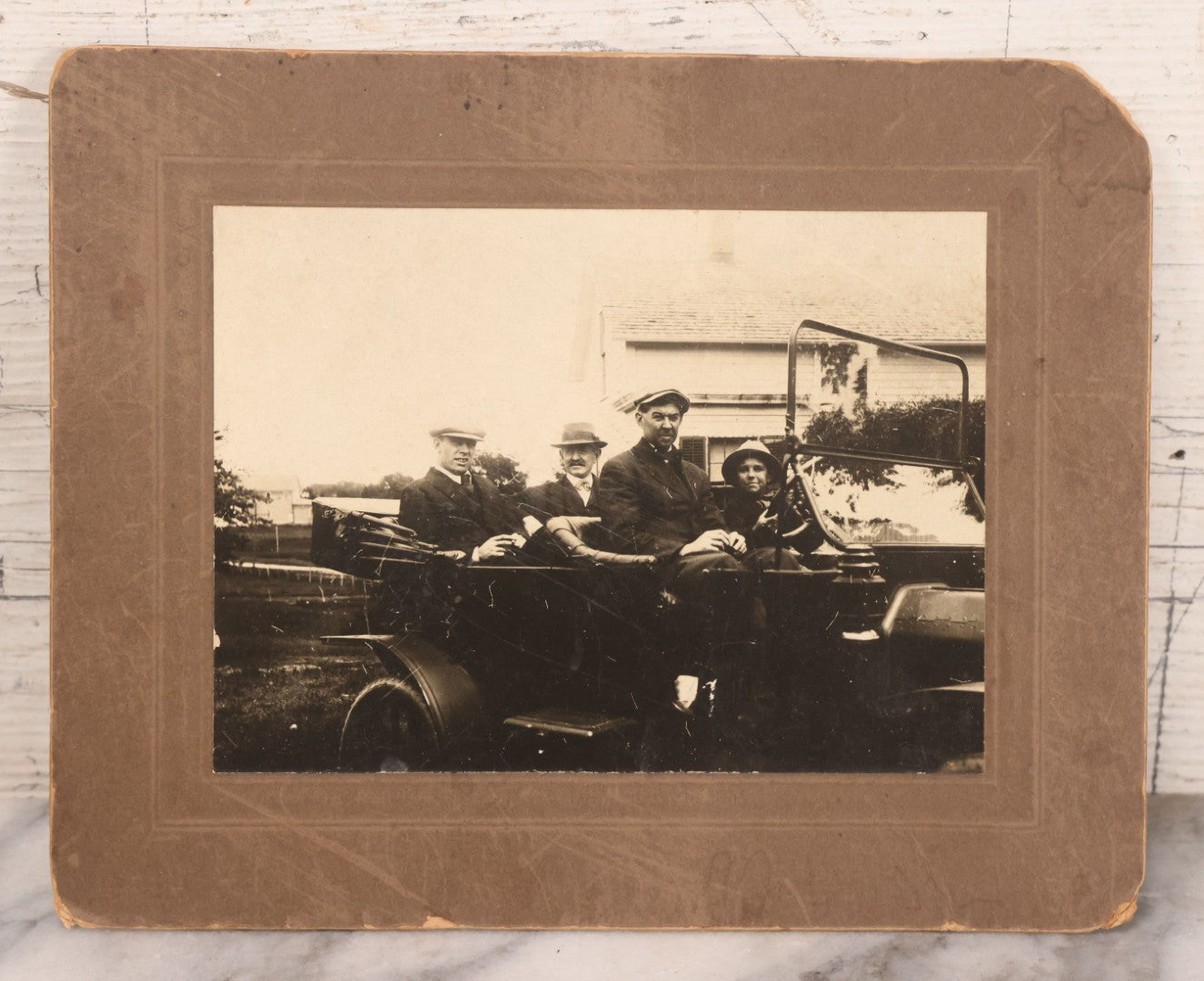 Lot 090 - Antique Boarded Photograph Of Three Men And Young Boy In Hats Driving In Early Automobile