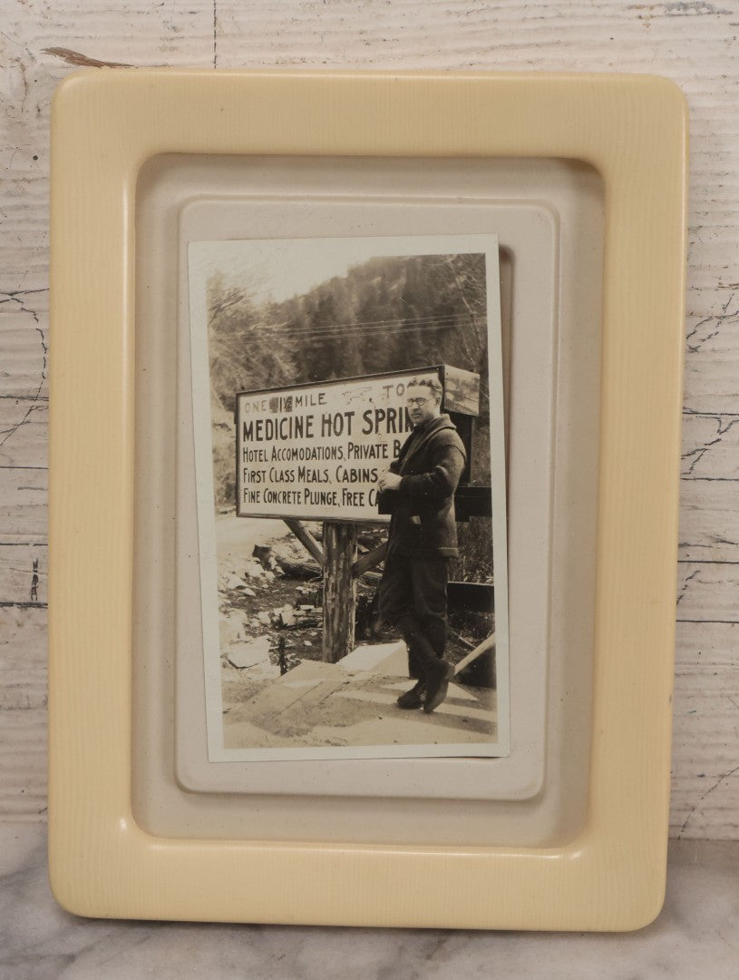 Lot 094 - Vintage Snapshot Photograph Of Man In Glasses Posing Beside Sign For Medicine Hot Springs, In Celluloid Frame