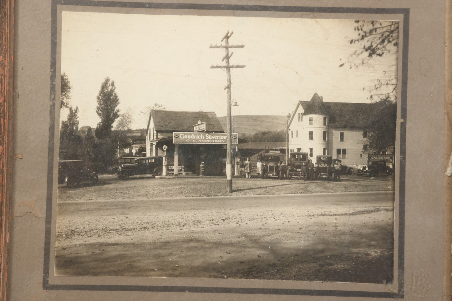 Lot 118 - Antique Boarded Photograph Of Early Gas Station With Many Automobiles Visible, Sign For Goodrich Silvertown Tires, C.E. Anderson, Richfield, In Frame, As Found, 13-3/4" x 11-1/4"