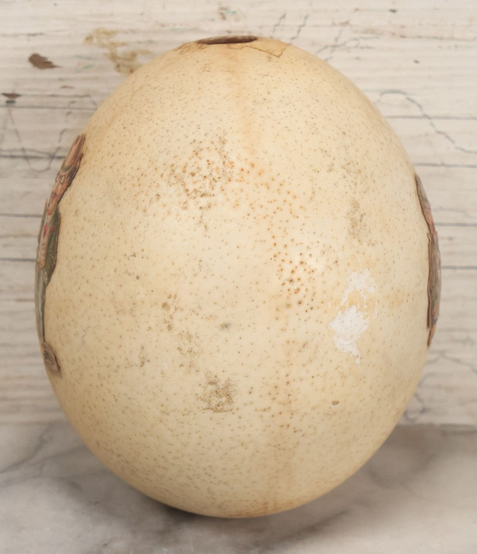 Lot 017 - Antique Genuine Ostrich Egg Specimen With Two Applied Victorian Die Cut Scraps Of Cheeky Caricatures, Note Originally Had More Scraps Attached, As Found
