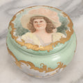 Lot 019 - Antique Hand Painted French Limoges Porcelain Dresser Box With Painting Of Brunette Woman In Extravagant Hat On Lid, With Yellow Painted Flowers, Artist Signed L.C.K. Dated 1894, With Purple "Belleek" Hallmark