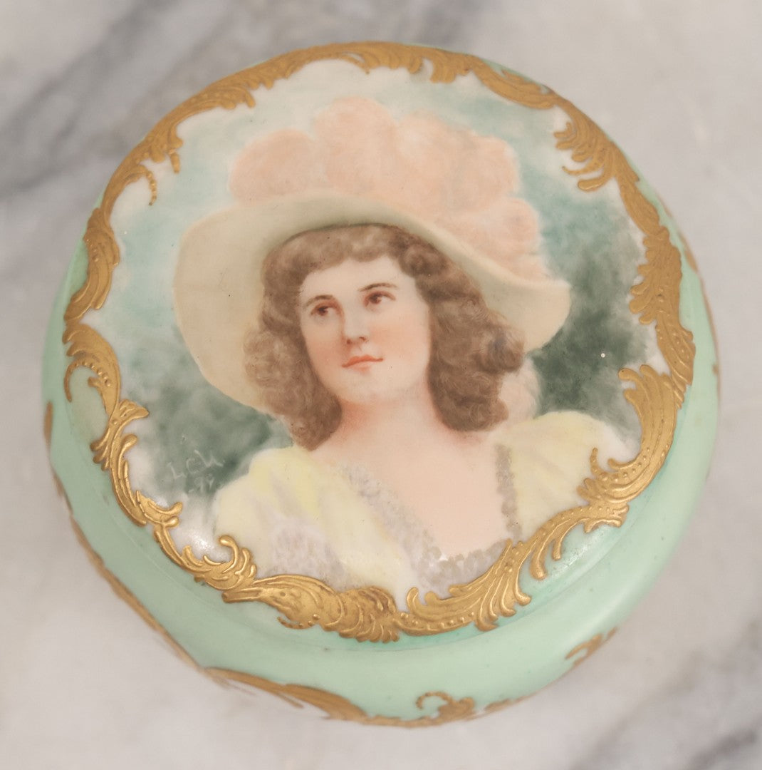 Lot 019 - Antique Hand Painted French Limoges Porcelain Dresser Box With Painting Of Brunette Woman In Extravagant Hat On Lid, With Yellow Painted Flowers, Artist Signed L.C.K. Dated 1894, With Purple "Belleek" Hallmark