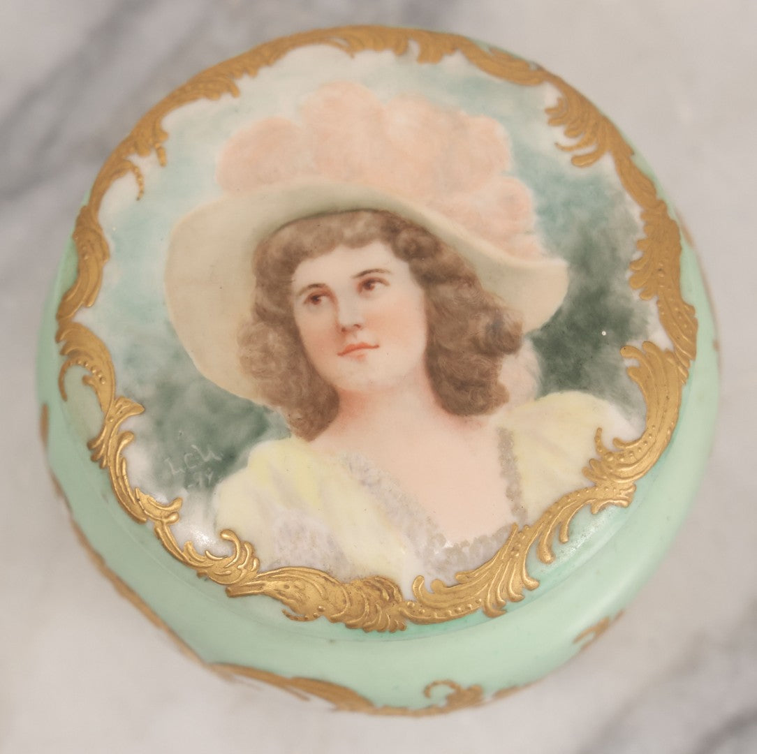 Lot 019 - Antique Hand Painted French Limoges Porcelain Dresser Box With Painting Of Brunette Woman In Extravagant Hat On Lid, With Yellow Painted Flowers, Artist Signed L.C.K. Dated 1894, With Purple "Belleek" Hallmark