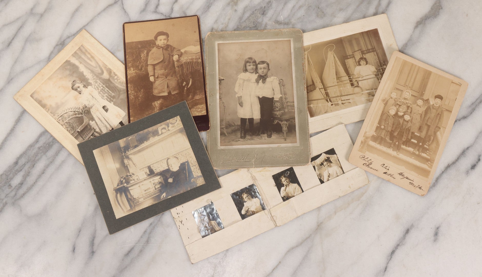 Lot 070 - Grouping Of Seven Antique Photographs Of Children, Including Makeshift Frame Of Girl In Four Views, Children Posing On New York City Stoop, Children In Cribs, Boy Posing With Toys