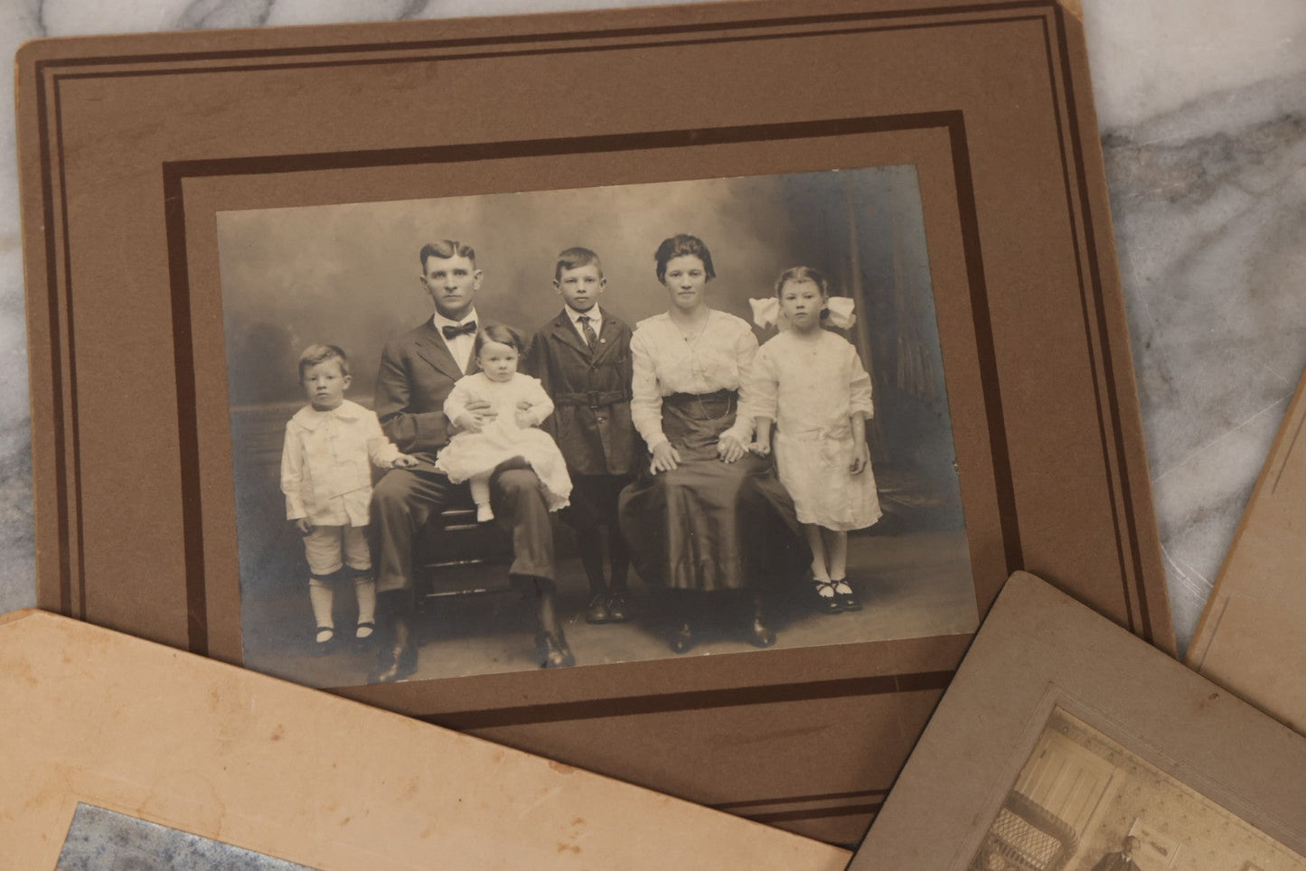 Lot 080 - Grouping Of Seven Antique Boarded Photographs Including Hunters Posing With Shotgun, Business Men In Bowler Hats, And Family Of Six