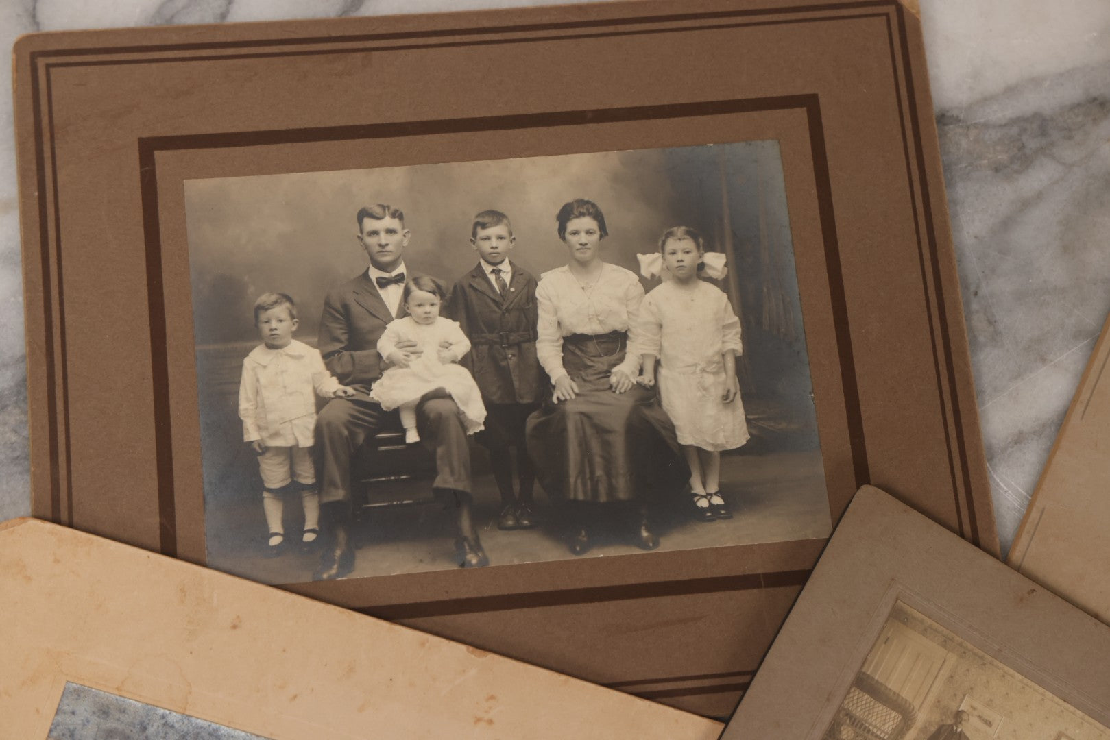 Lot 080 - Grouping Of Seven Antique Boarded Photographs Including Hunters Posing With Shotgun, Business Men In Bowler Hats, And Family Of Six
