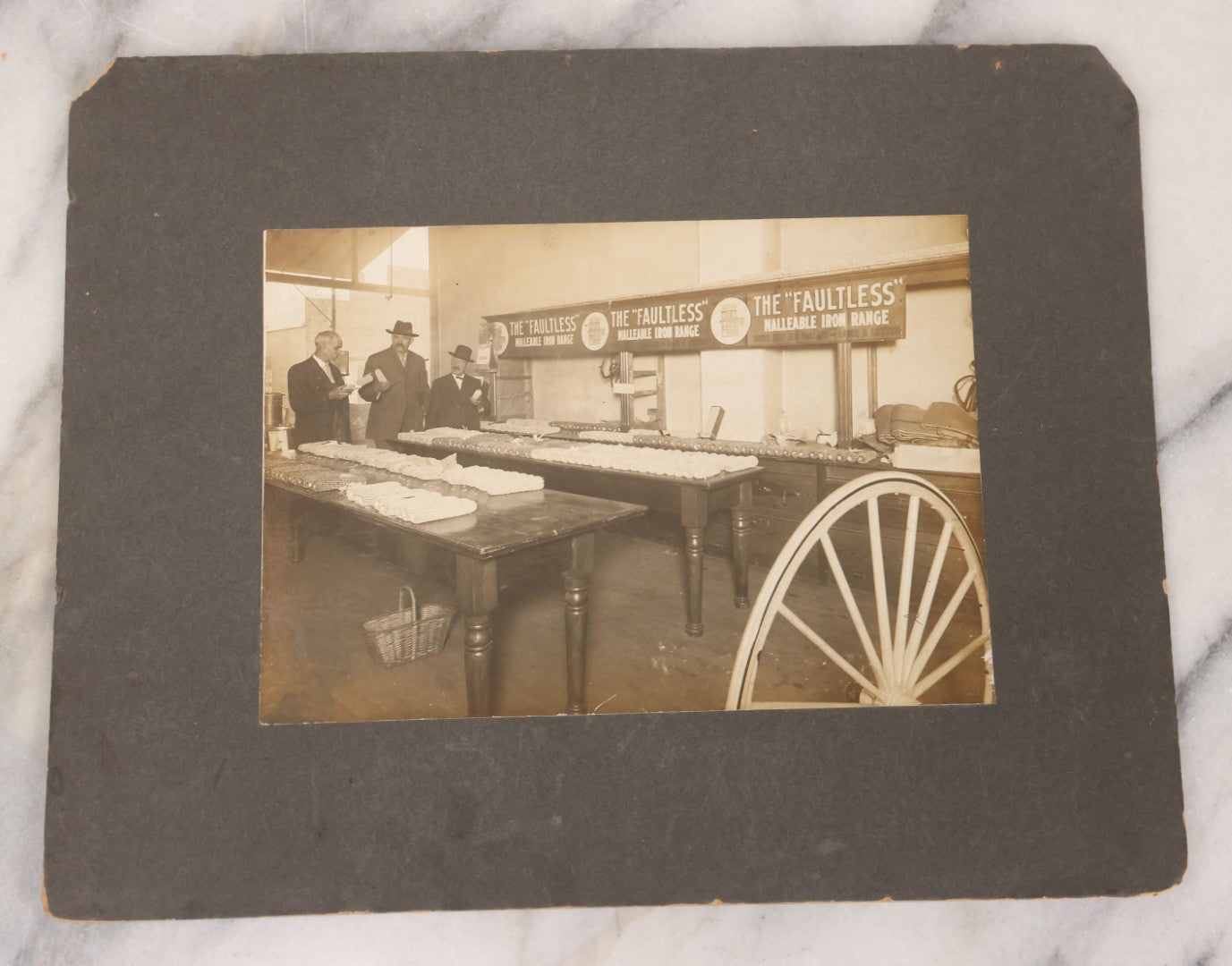 Lot 084 - Antique Boarded Occupational Photograph Of Three Men Inspecting A Large Variety Of Corn, With Advertisement For "The 'Faultless' Malleable Iron Range" In Background