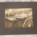 Lot 084 - Antique Boarded Occupational Photograph Of Three Men Inspecting A Large Variety Of Corn, With Advertisement For "The 'Faultless' Malleable Iron Range" In Background