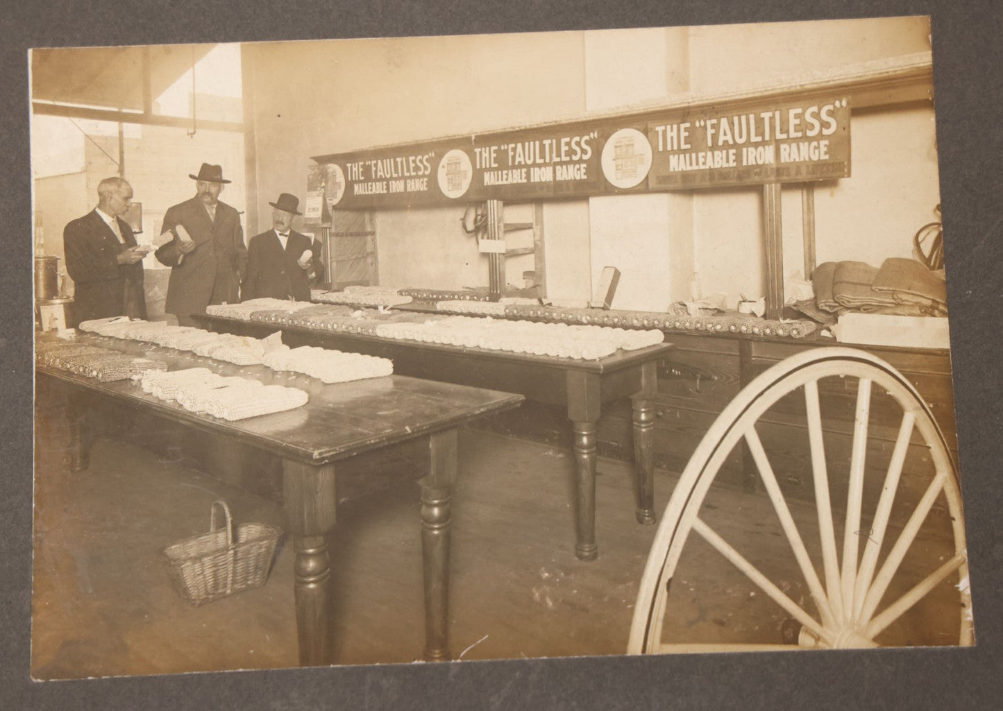 Lot 084 - Antique Boarded Occupational Photograph Of Three Men Inspecting A Large Variety Of Corn, With Advertisement For "The 'Faultless' Malleable Iron Range" In Background