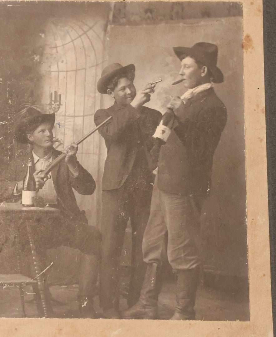 Lot 086 - Antique Boarded Studio Photograph Of Four Boys Drinking, Smoking, And Pointing Guns At Their Buddy