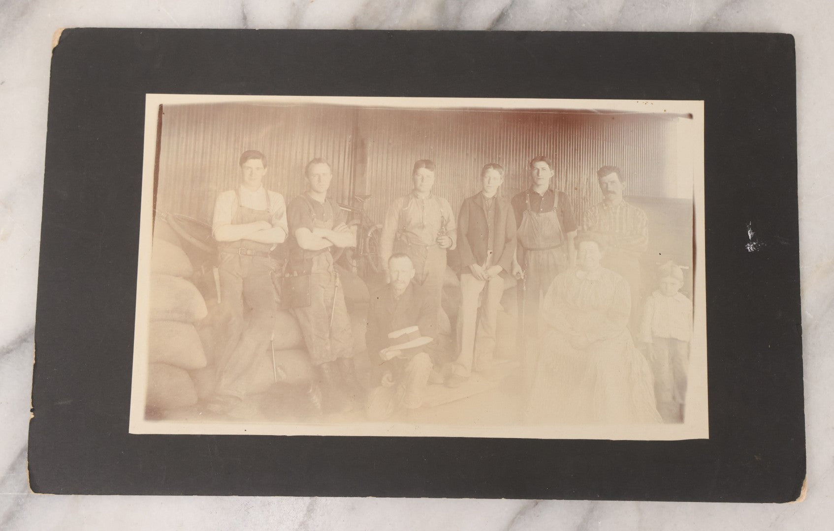 Lot 088 - Antique Boarded Occupational Photograph Of Group Of Workers, Unknown Trade, Posing On A Pile Of Sacks With Bicycles In Background