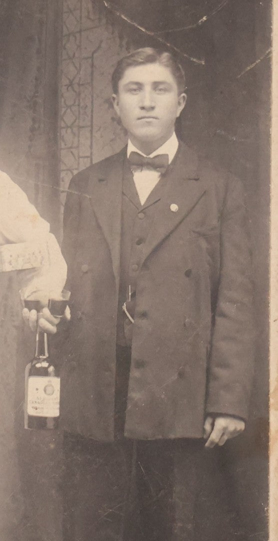 Lot 100 - Antique Trimmed Boarded Photograph Of Bartender Posing With Liquor Bottle, Glasses, And Cigar Box, With Two Men, Detailed Writing On Verso Likely In Polish