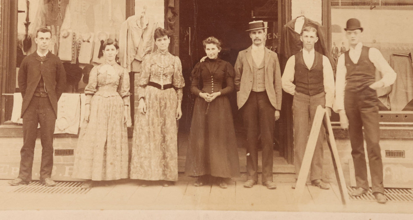 Lot 111 - Antique Boarded Occupational Photograph Of Workers And Dressmakers Posing Outside Their Shop, With Many Signs And Advertisements In Photo, Note Photo Has Large Crease Through Center On Verso