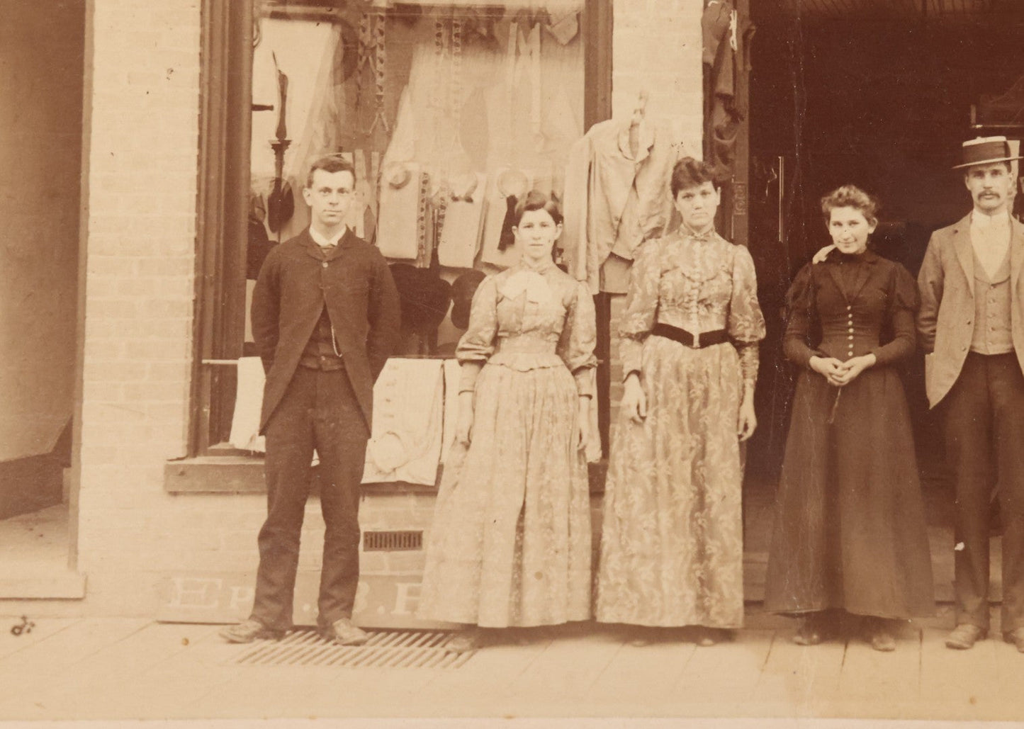 Lot 111 - Antique Boarded Occupational Photograph Of Workers And Dressmakers Posing Outside Their Shop, With Many Signs And Advertisements In Photo, Note Photo Has Large Crease Through Center On Verso