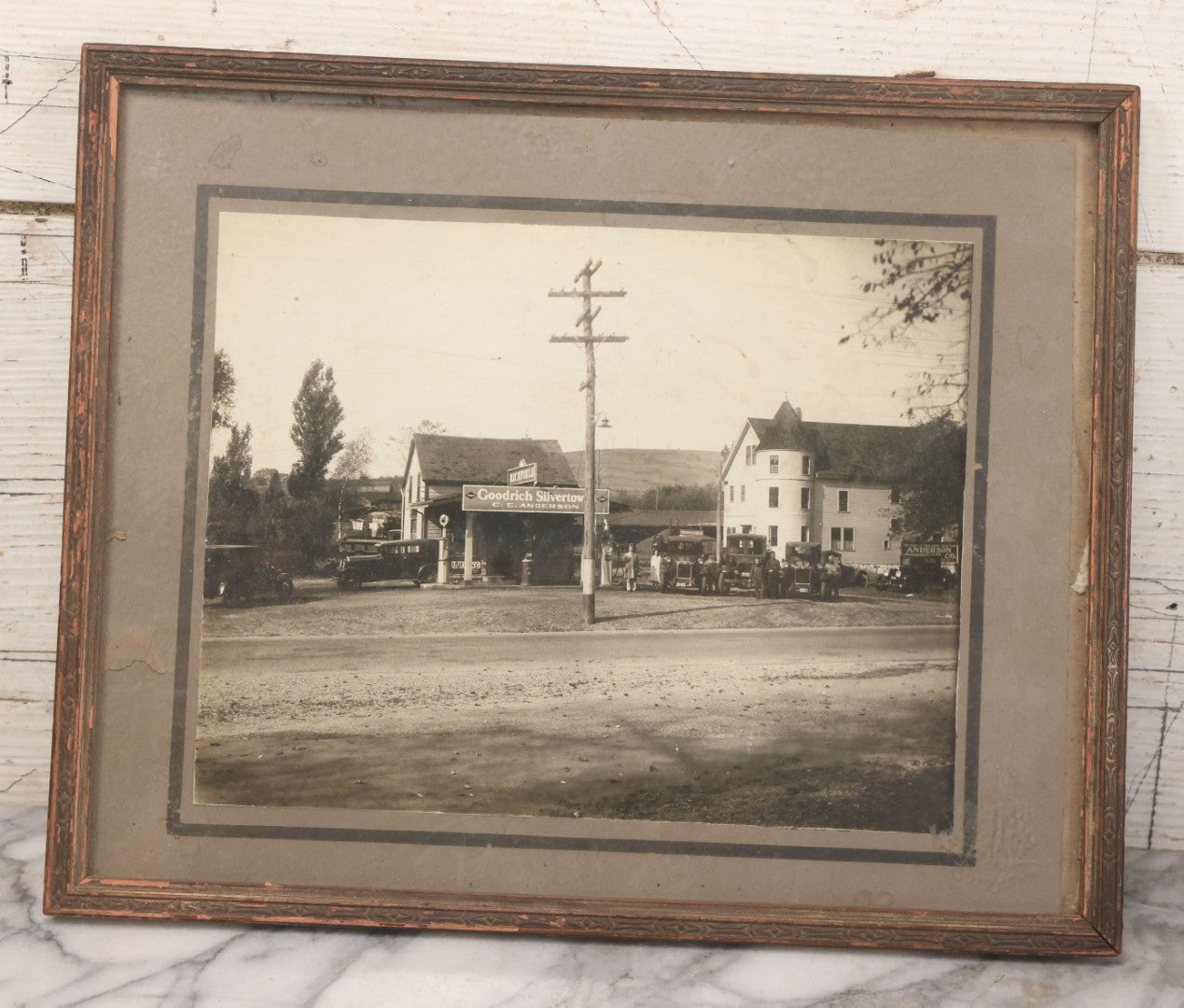 Lot 118 - Antique Boarded Photograph Of Early Gas Station With Many Automobiles Visible, Sign For Goodrich Silvertown Tires, C.E. Anderson, Richfield, In Frame, As Found, 13-3/4" x 11-1/4"