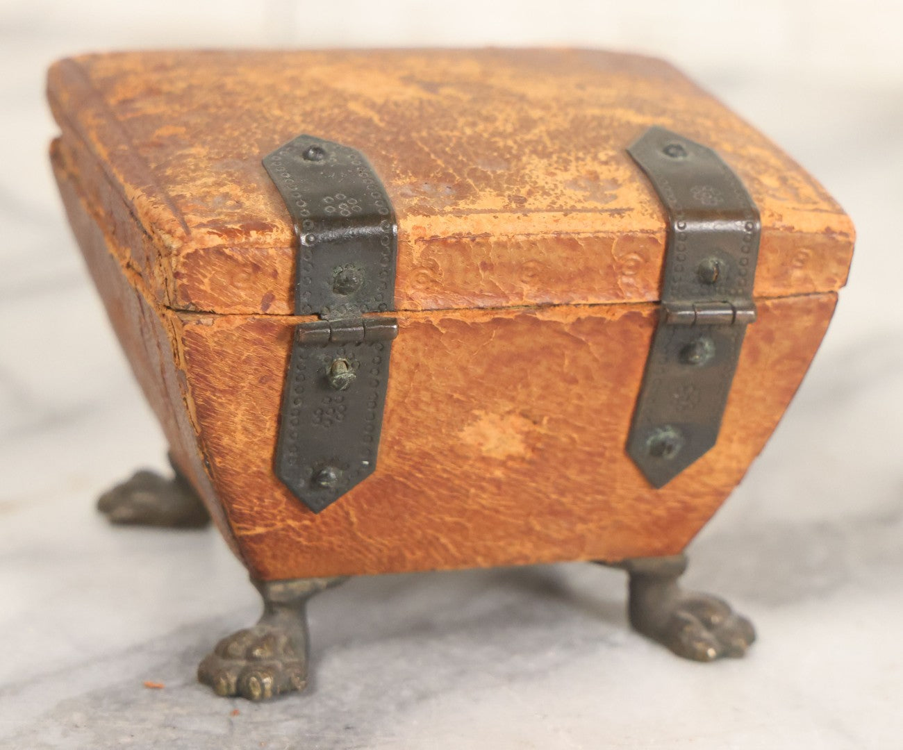 Lot 030 - Antique Leatherette Footed Stash Box With Paper Interior, Black Metal Strap Hinges, And Cloth Feet