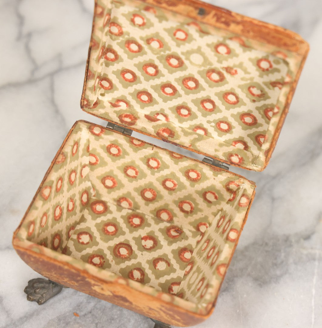 Lot 030 - Antique Leatherette Footed Stash Box With Paper Interior, Black Metal Strap Hinges, And Cloth Feet