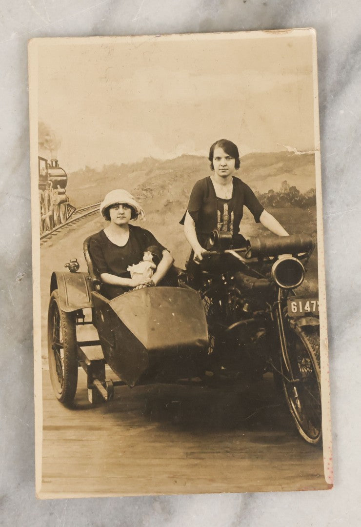 Lot 072 - Antique Real Photo Postcard R.P.P.C. Of Two Women Posing On An Early Indian Motorcycle With Sidecar, Woman In Hat Holding Kewpie Doll