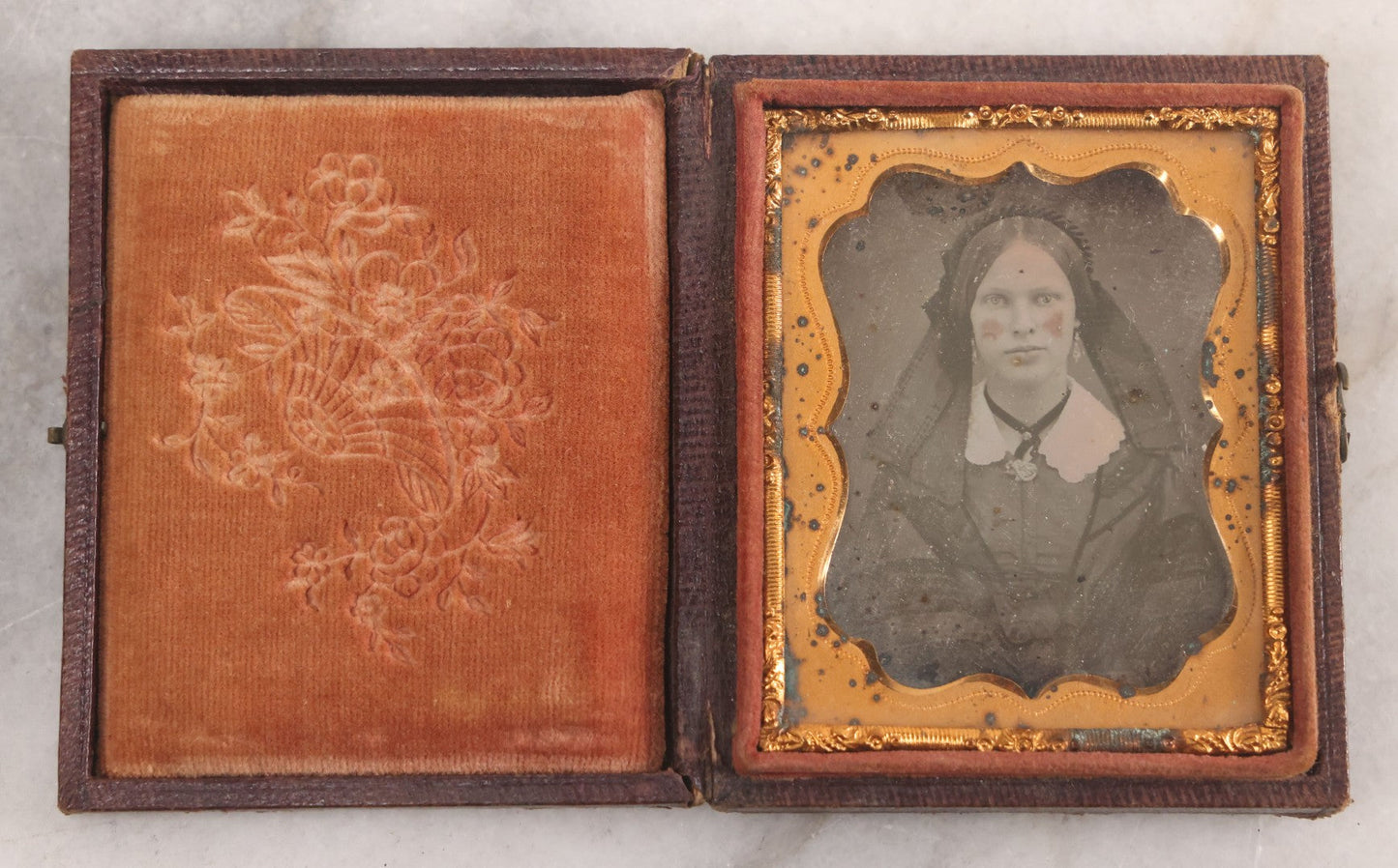 Lot 015 - Antique 1/9th Plate Daguerreotype Photograph Of Young Woman With Striking Eyes, White Collar, And Bonnet With Long Dark Lappets, In Full Intact Leatherette Union Case With Rose Motif